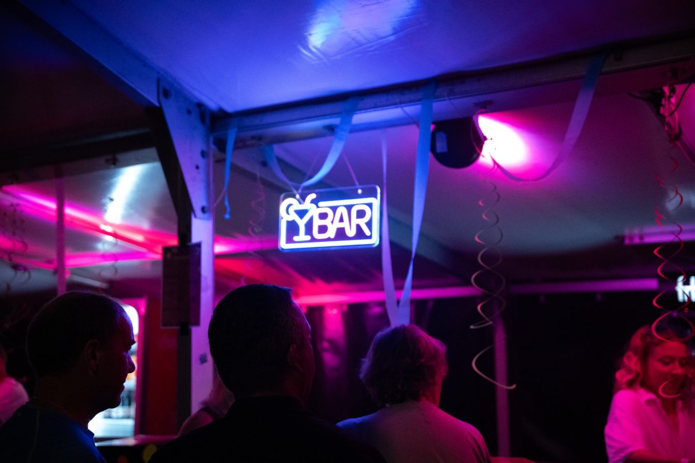 Bunte Neonlichter in einem Innenraum mit Menschen im Hintergrund.