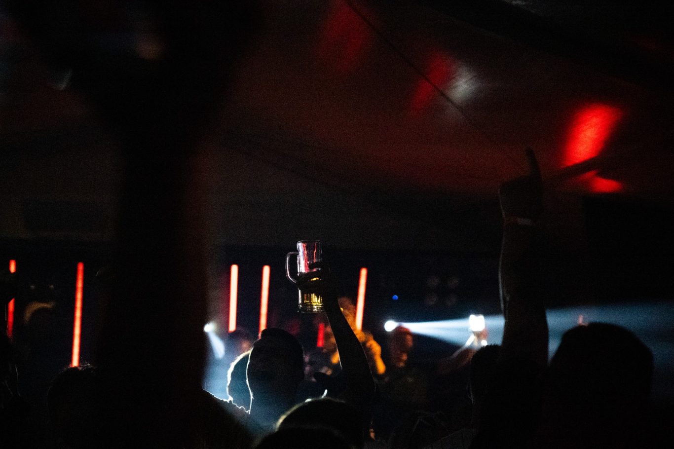 Dunkle Partyatmosphäre mit erhobenen Händen und farbigen Lichtern.